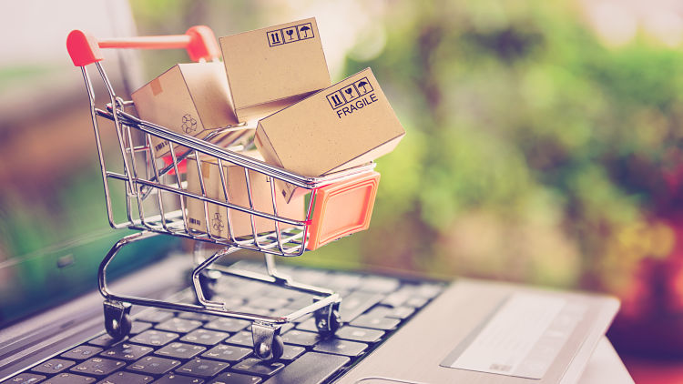 Online shopping and delivery service concept. Paper cartons in a shopping cart on a laptop keyboard