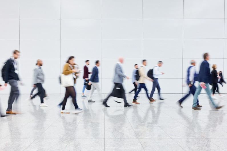 people walking through a large marble lobby