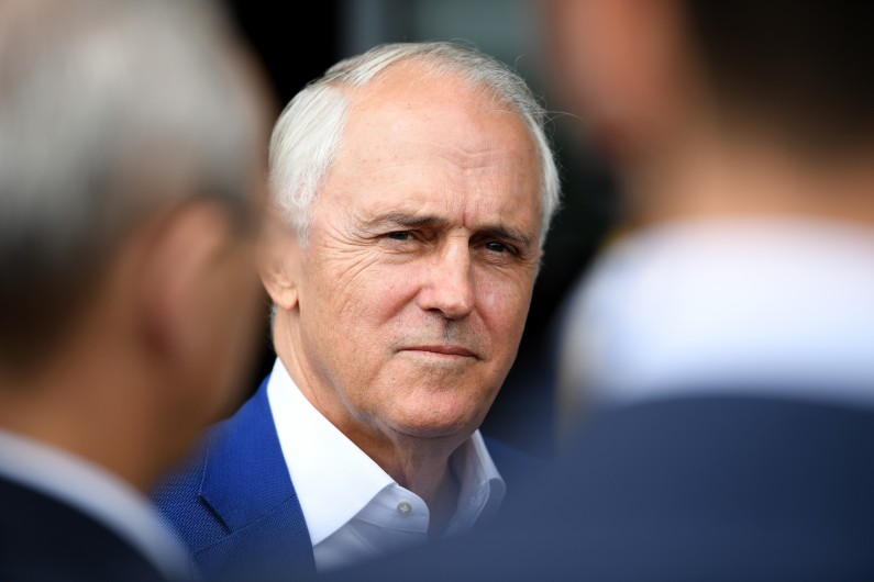 Former prime minister Malcolm Turnbull head shot in focus between two out of focus mens' heads