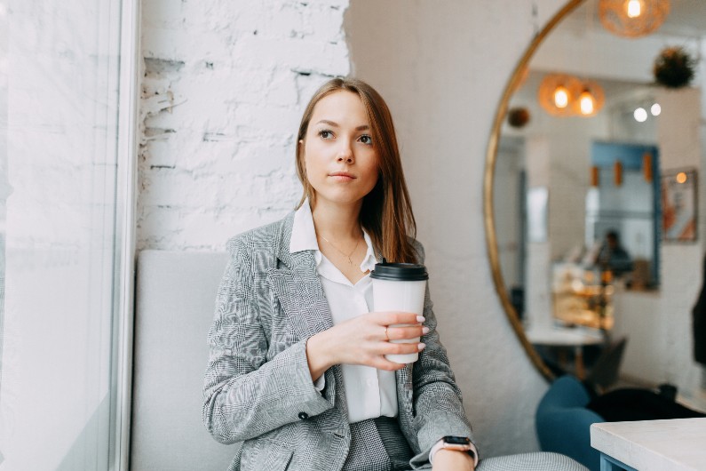 business woman holding a coffee looking anxious