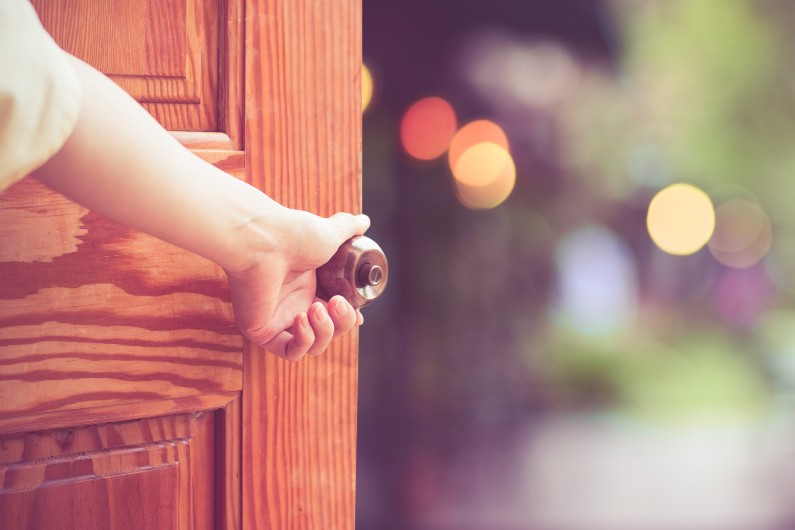 wooden door being held open, lights in background