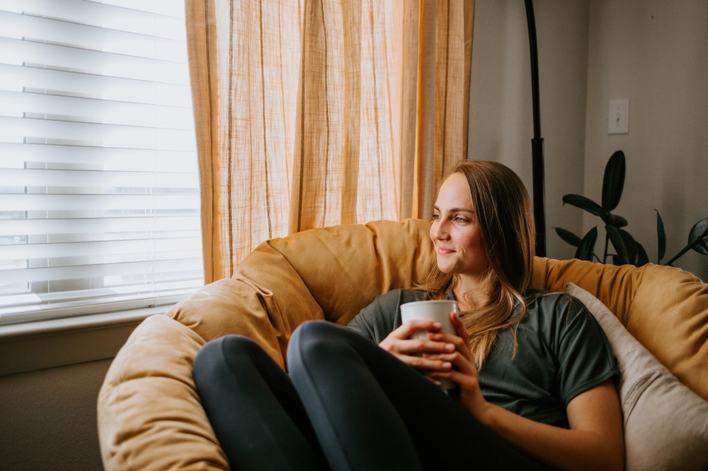 content-woman-papasan chair-Woman relaxing at home with mug